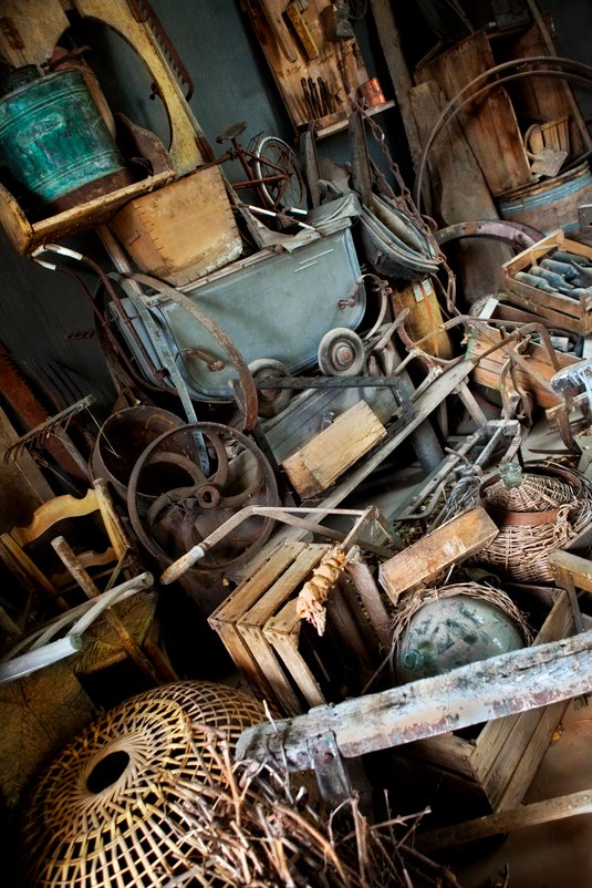 Old cluttered shed filled with tools, metal parts, and wood debris