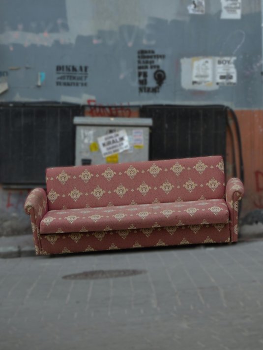 Vintage red couch left on the street against a wall with posters