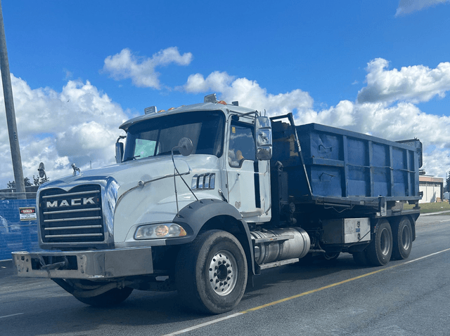 Roll-off dumpster truck delivering a blue bin in Guelph Ontario